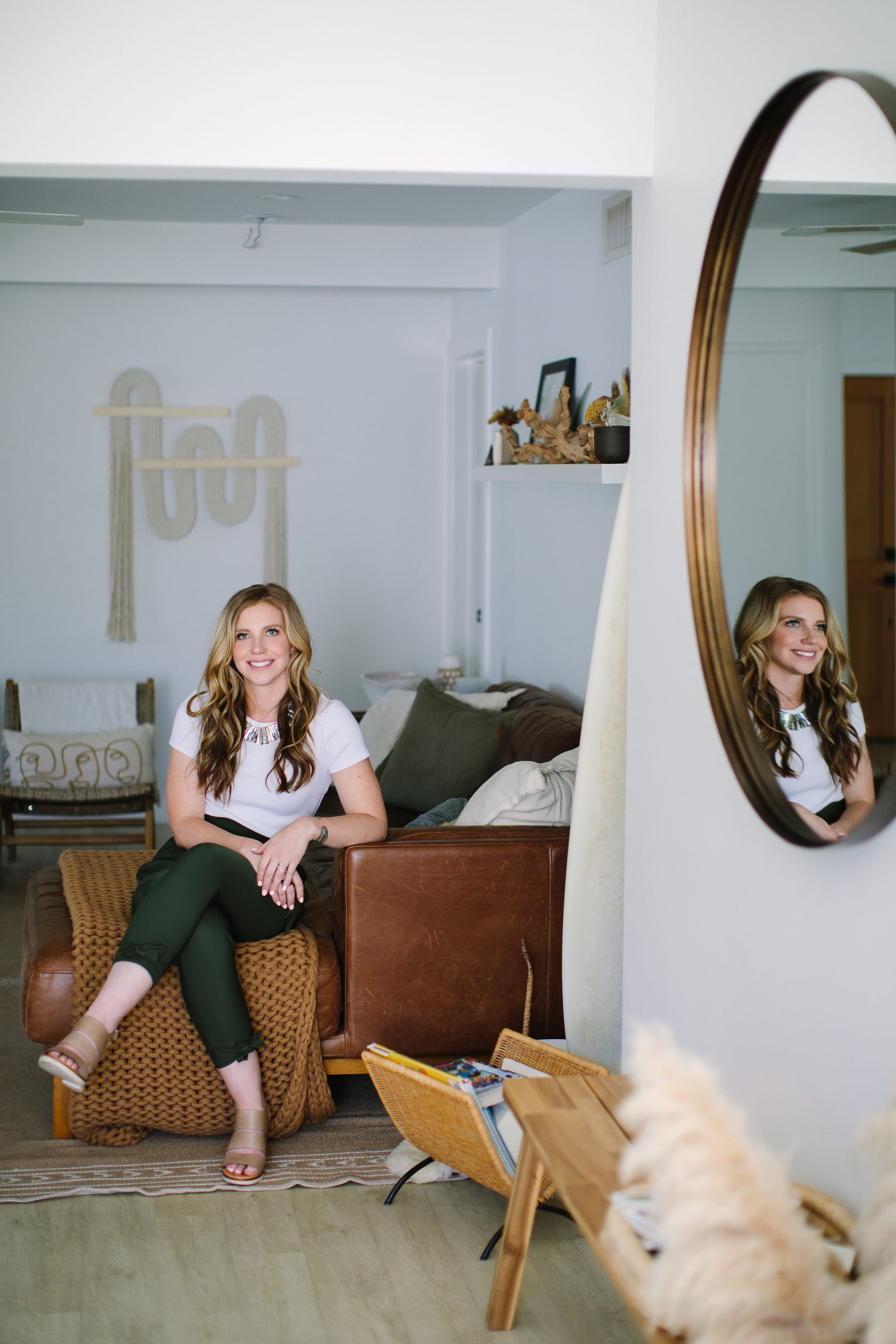 Christina Mathieson, LMFT, sitting on a leather couch in the My Mental Climb practice space, with a circular mirror reflecting her on the right.